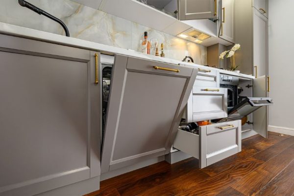 Modern built-in dishwasher seamlessly integrated into a white kitchen cabinet with stainless steel handle