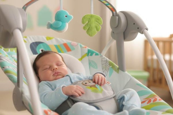 Cozy newborn relaxing in Bright Starts 6-Speed Portable Baby Swing with plush toys attached