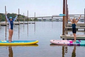 Inflatable paddle board gliding on calm lake water with beginner paddler