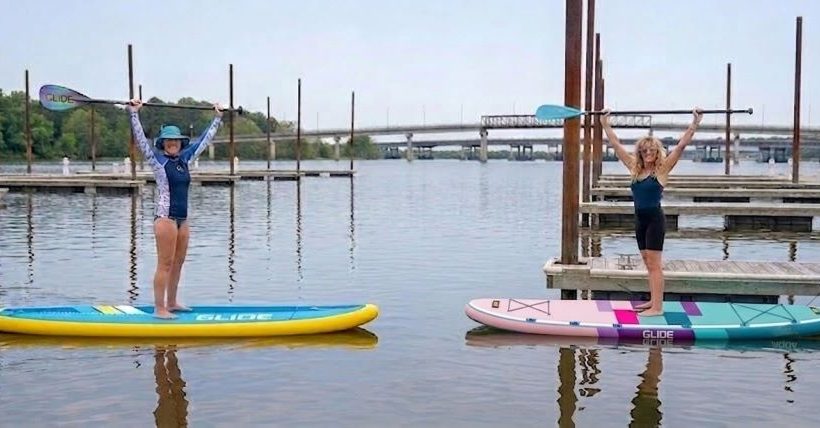 Inflatable paddle board gliding on calm lake water with beginner paddler