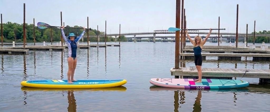 Inflatable paddle board gliding on calm lake water with beginner paddler