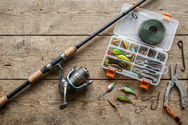 Flat lay of affordable rugged fishing gear on a weathered wooden table.